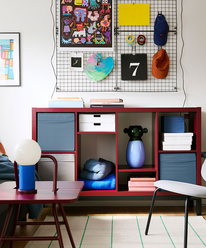 A living room features a brown-red/black KALLAX shelving unit with compartments, placed against a Wall with decorations.