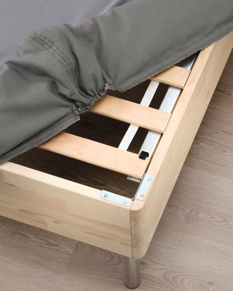 Minimalist bedroom with LYNGÖR mattress base and cover, supported by BJORLI legs, featuring a natural wood frame.